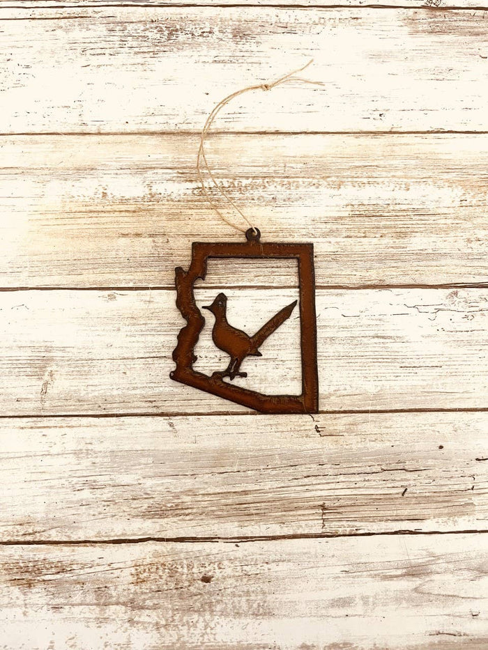 Rusty metal ornament shaped as the Arizona outline with a roadrunner silhouette inside a square frame and a hanging loop.