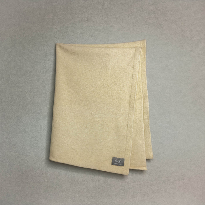 Beige baby blanket with a brand label on a gray background