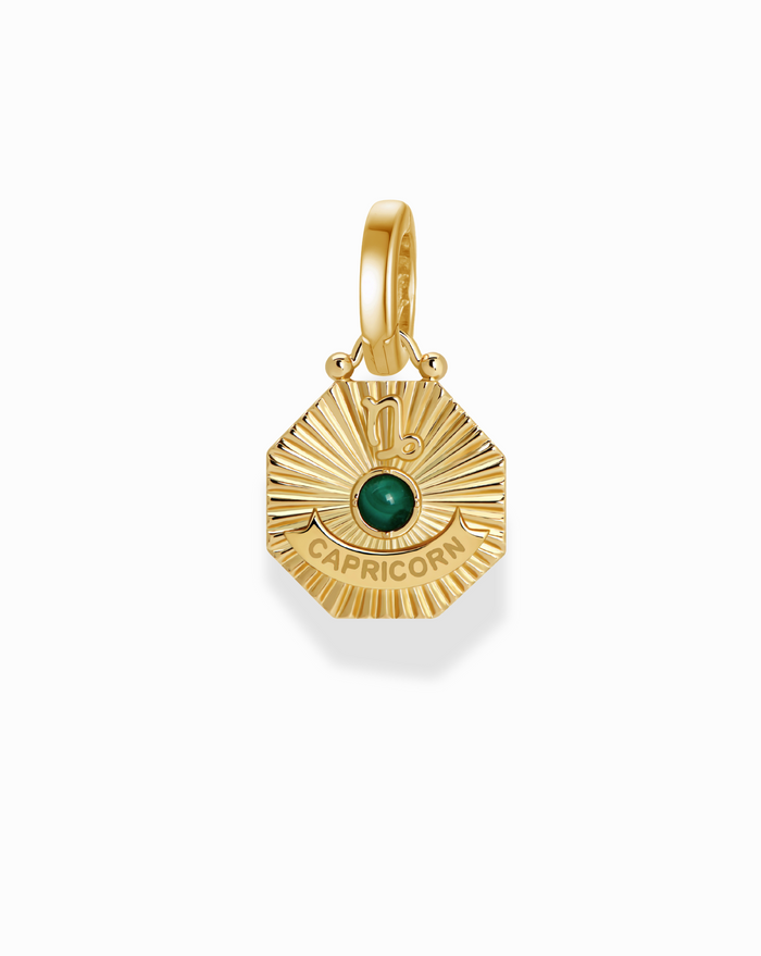 Close-up of the Becca Zodiac Charm, a gold Capricorn pendant with a green stone. "Capricorn" text visible.
