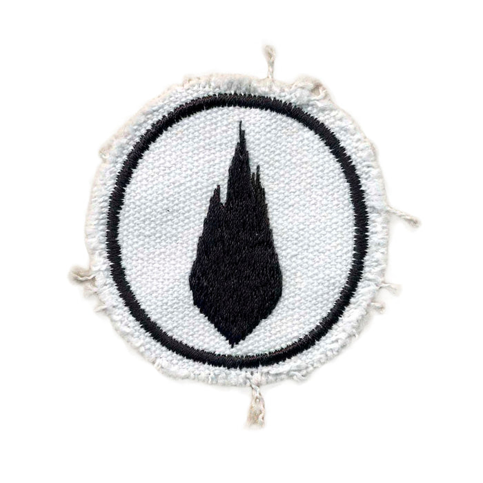 A round white fabric patch from Thousand Foot Krutch features a black flame-shaped symbol in the center with a rough, frayed edge and a thin black circular border.