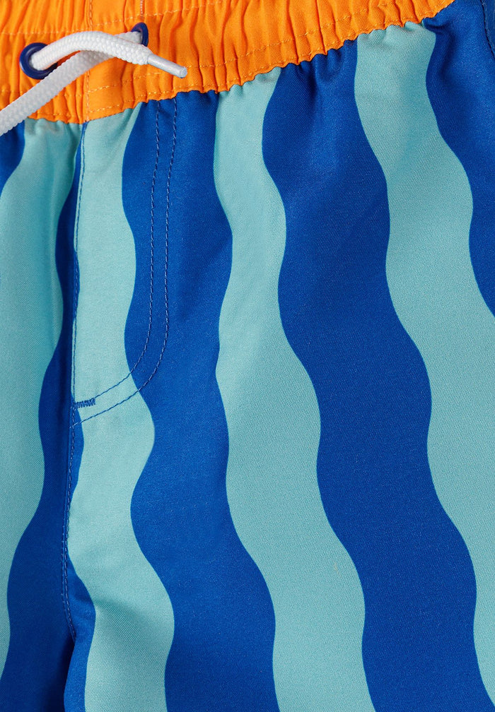 Detail of boys' swimming shorts with blue wavy pattern and elastic waistband.