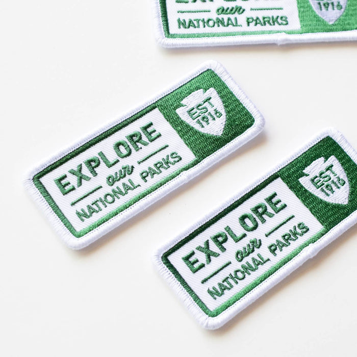 Several embroidered patches showing the Explore Our National Parks design with green borders arranged diagonally.