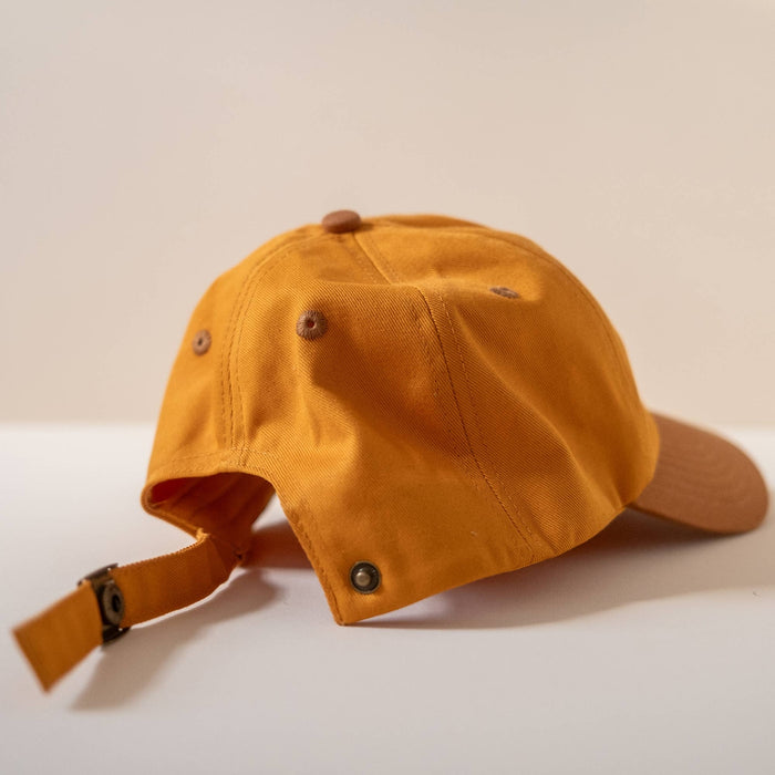 Back view of orange cap showing adjustable strap and metal buckle