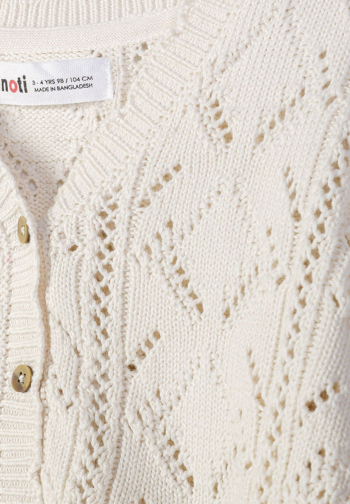 Detail of a white cotton cardigan for girls, featuring a button front and pointelle knit.