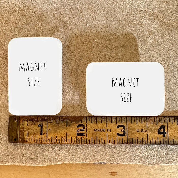 Two white rounded wood magnets labeled Magnet Size on a wooden surface with a measuring tape underneath.