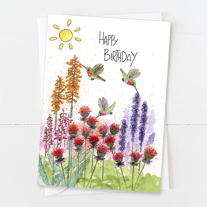 Happy Birthday card featuring a bright garden scene with hummingbirds and colorful flowers