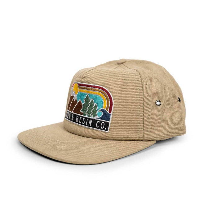 Tan Landscape Trucker Hat with colorful embroidered patch depicting mountains trees and a retro rainbow.
