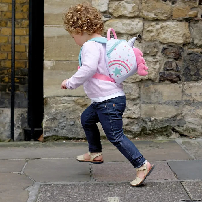 Little girl running along a path whilst wearing a Littlelife Unicorn Toddler Backpack