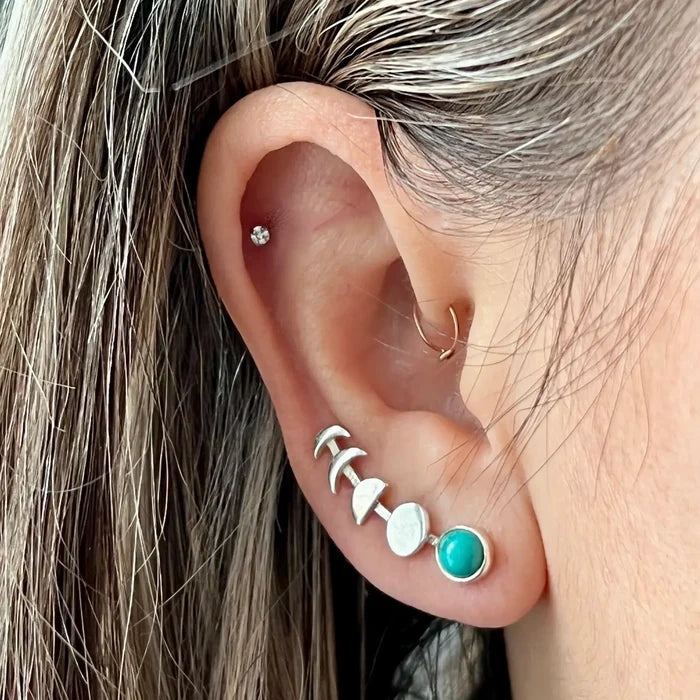 Moon Phases Silver Ear Climber curves along the earlobe with silver crescents and turquoise stone, plus a small diamond stud in cartilage