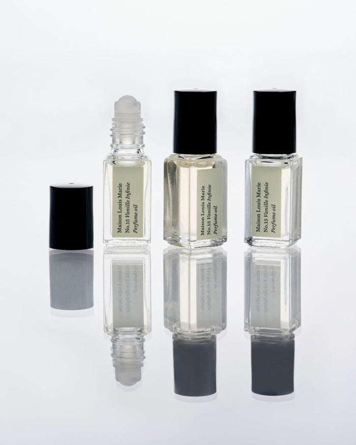 Three small perfume bottles with black caps on a white background