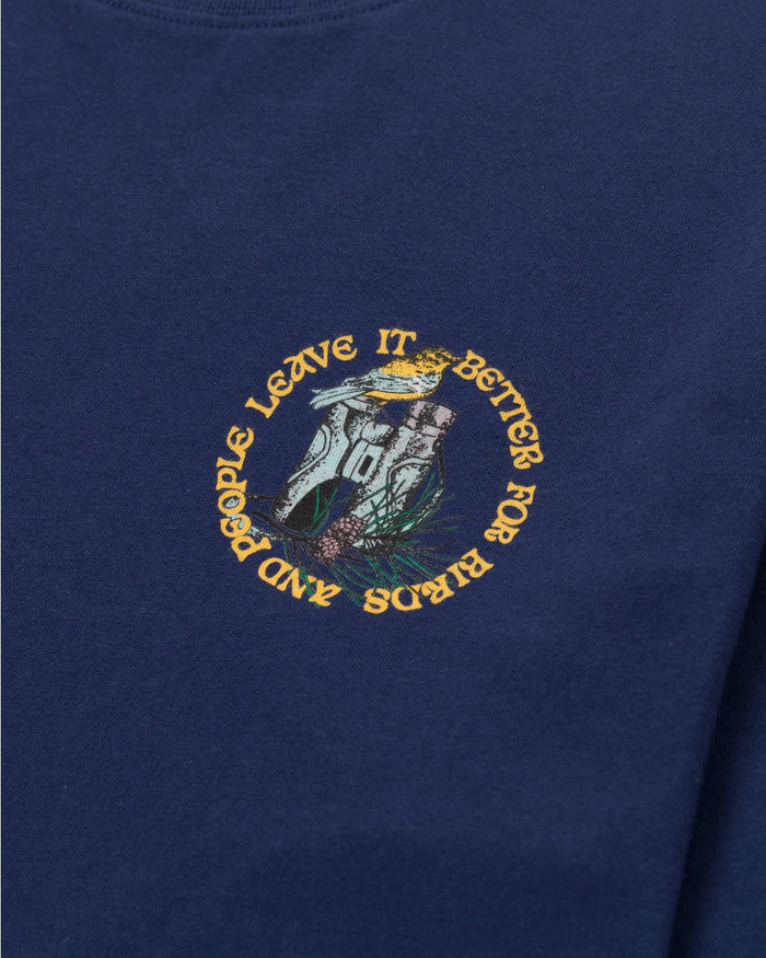 Navy Parks Project X Audubon long sleeve tee chest print with a circular emblem showing a bird and landscape inside and bold yellow text around the edge