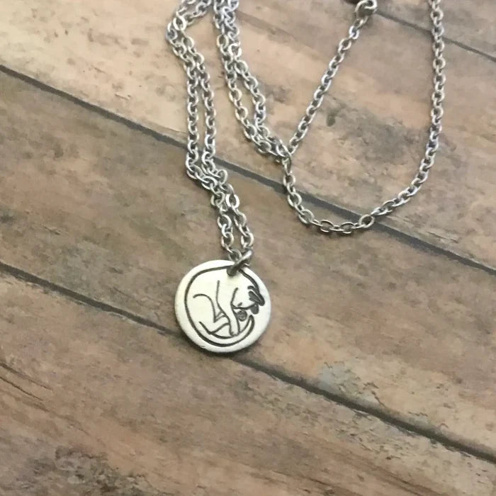 Close up of round sleeping cat pendant on a silver chain necklace