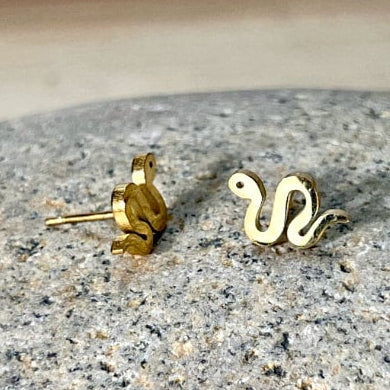 Gold and silver snake stud earrings on a speckled gray surface