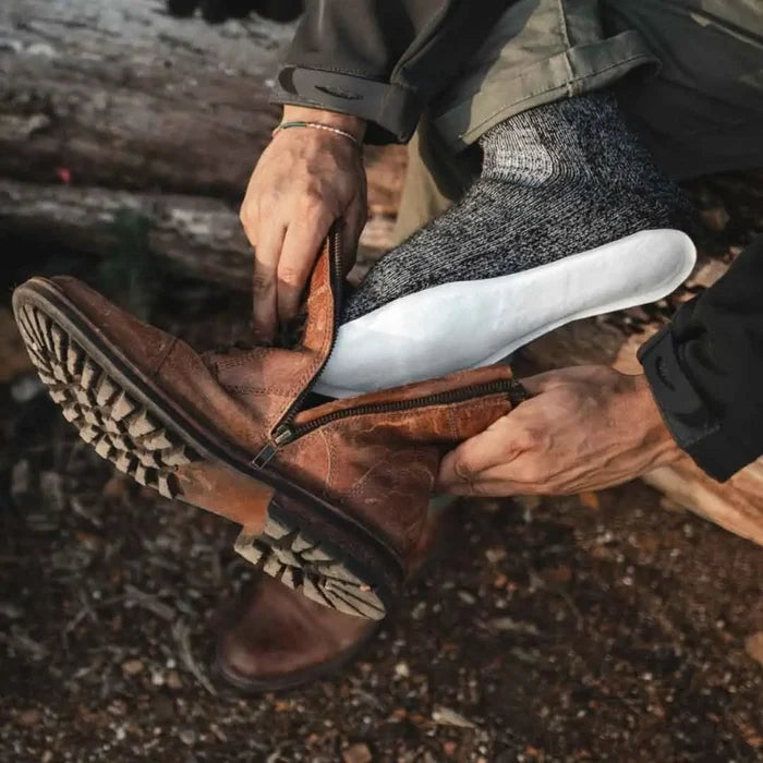 Thaw disposable foot warmersbeing worn over socks and being placed in to a boot