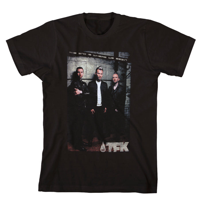 Black T-shirt by Thousand Foot Krutch featuring a printed photo of three men in front of a wall, with “The End Is Where We Begin” above and the TFK logo below the image.