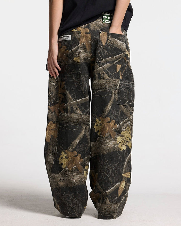 V1 CARPENTER PANTS REALTREE BLACK - black realtree camo carpenter pants, back view on female model - Cold Culture
