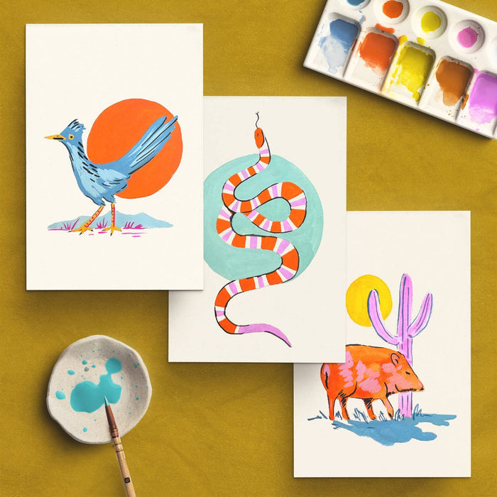 Southwest Animals watercolor kit cards on a mustard backdrop featuring a blue bird, striped snake, desert scene and palette.