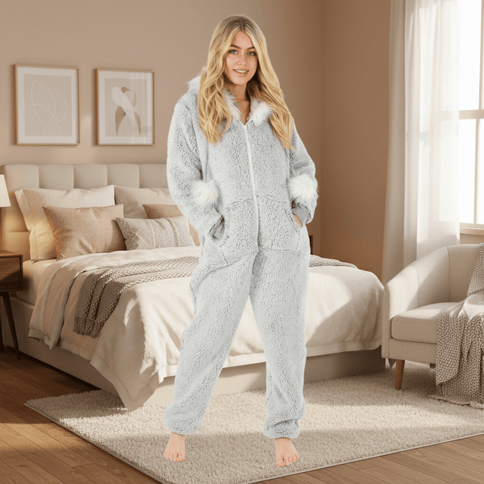 Woman wearing a grey onesie in a cosy bedroom