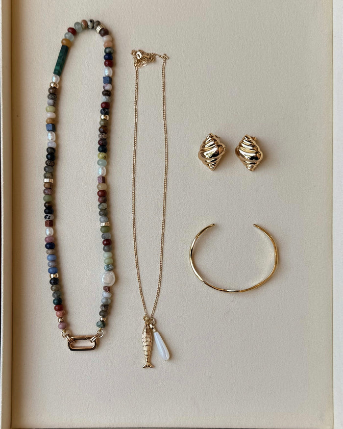 Set of jewelry including a necklace, bracelet, and earrings on a beige background