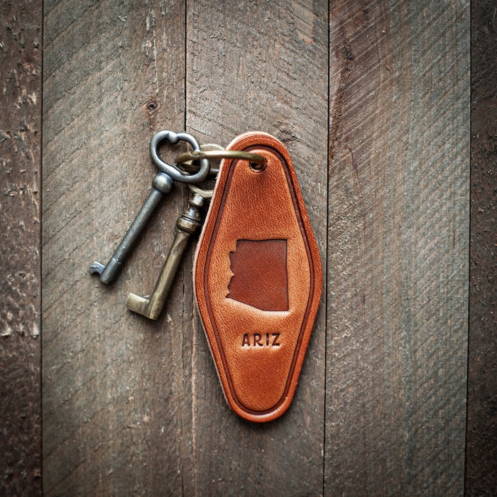 Arizona leather motel style keychain with a brass key and ring resting on wood