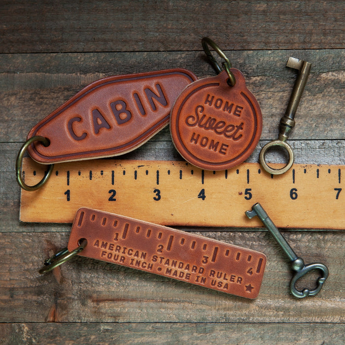 Cabin and home sweet home Arizona leather keychain set with keys and a ruler on a rustic surface