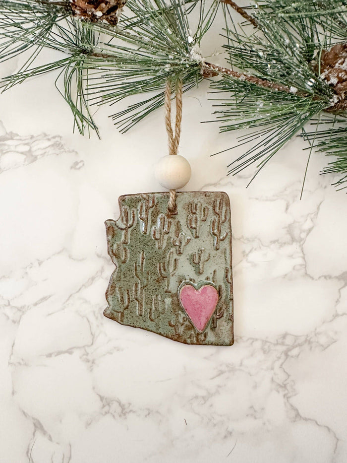 Arizona shaped ceramic ornament with cactus pattern and pink heart, hung on jute twine