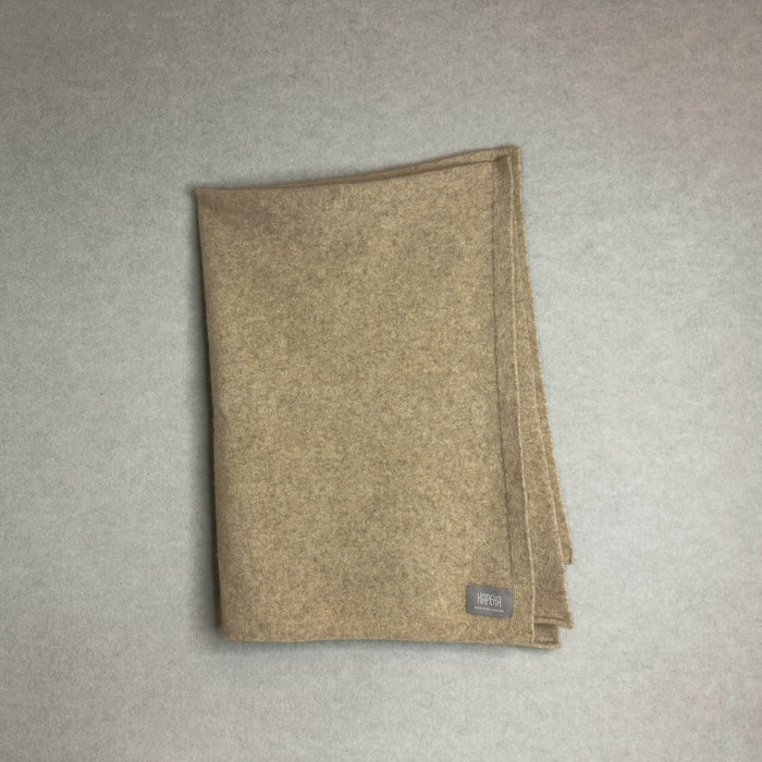 Beige baby blanket with a brand label on a gray background