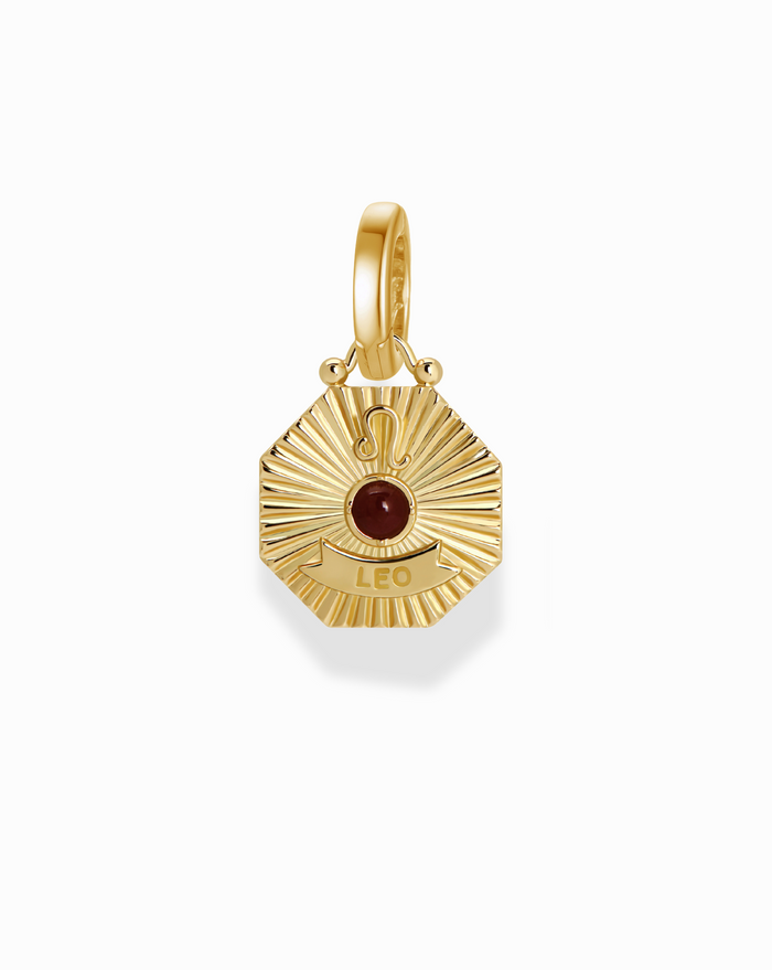 Close-up of the Becca Zodiac Charm featuring a gold pendant with the Leo symbol and a red gemstone.