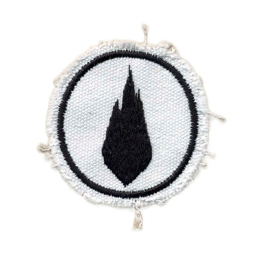 A round white fabric patch from Thousand Foot Krutch features a black flame-shaped symbol in the center with a rough, frayed edge and a thin black circular border.
