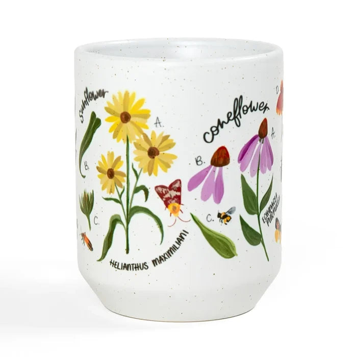 White speckled ceramic mug featuring yellow daisies and purple flowers with botanical labels.