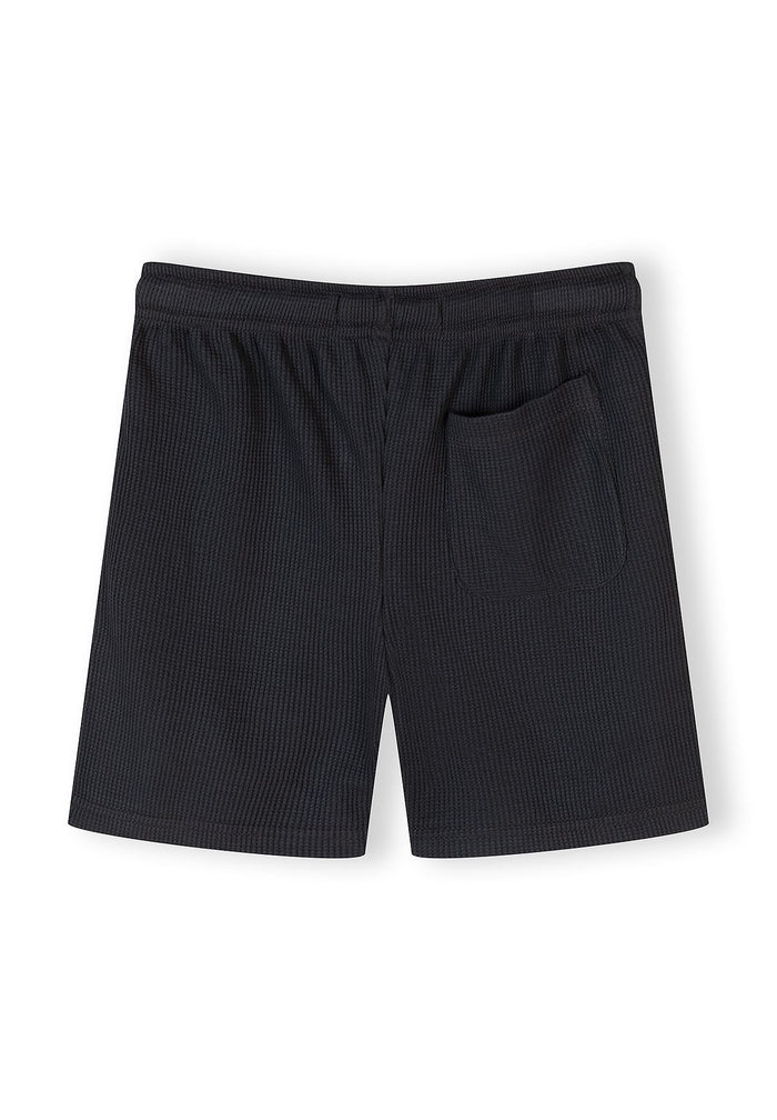 Back view of waffle-textured shorts with elasticated waistband and side pocket.