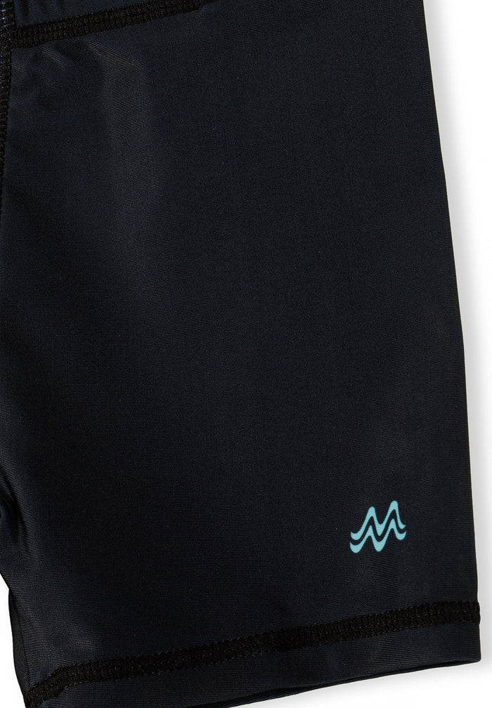 Detail of black swim shorts with elastic waistband and logo.