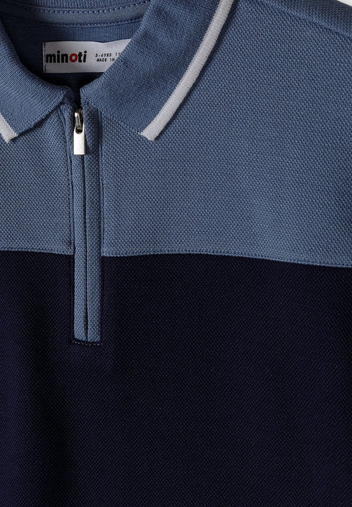 Detail of a boys' navy blue polo shirt with a zip-up collar and textured fabric.