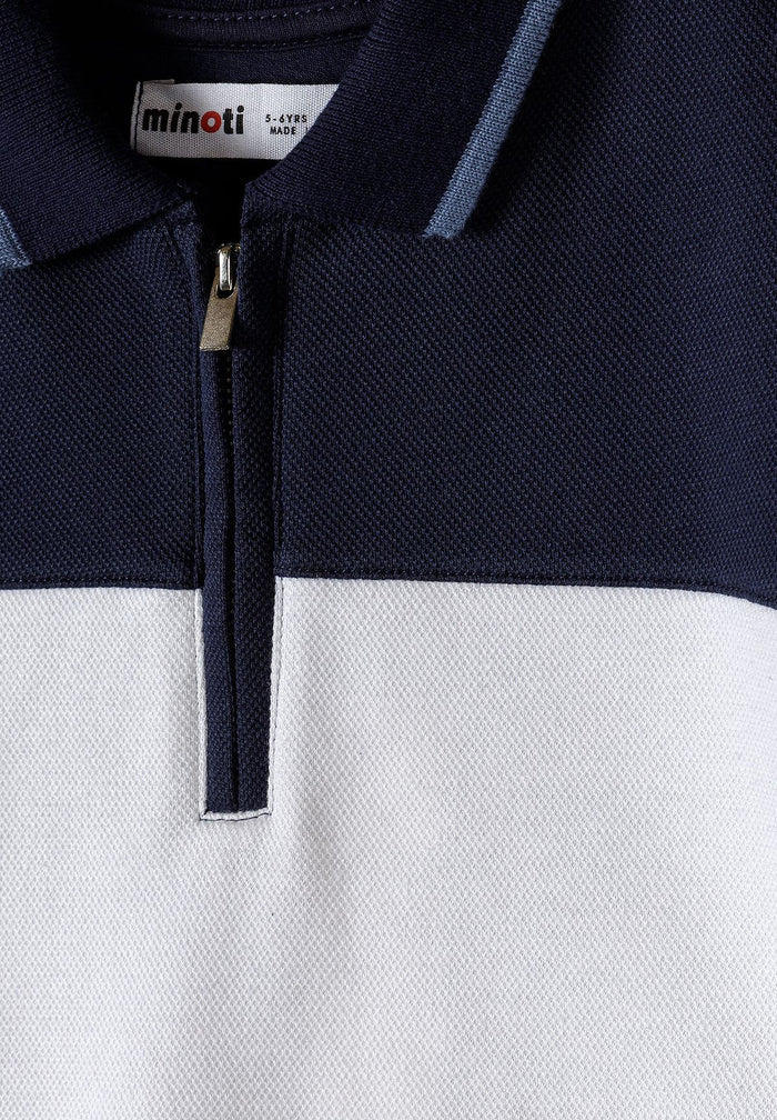 Close-up of a boys' navy and white polo with a zip collar and textured pique finish.