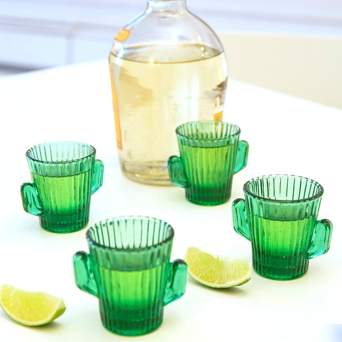 Set of four green ribbed cactus shaped shot glasses with lime wedges and a bottle in the background