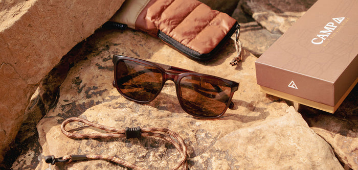 CAMP Crag sunglasses in brown frame on a rocky surface with braided cord pouch and box nearby