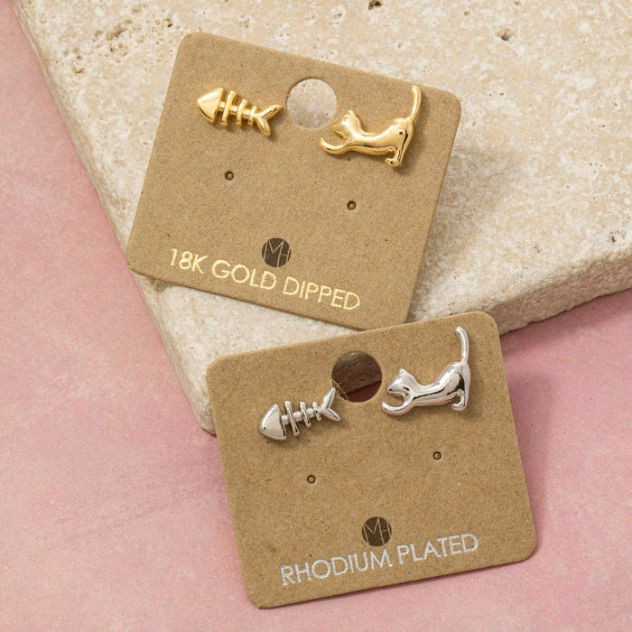 Gold dipped cat and fish stud earrings on a brown display card.