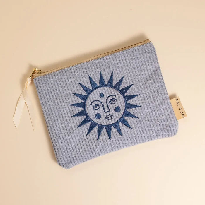 Pale blue corduroy small pouch with a dark blue sun and face embroidery and a gold zipper.