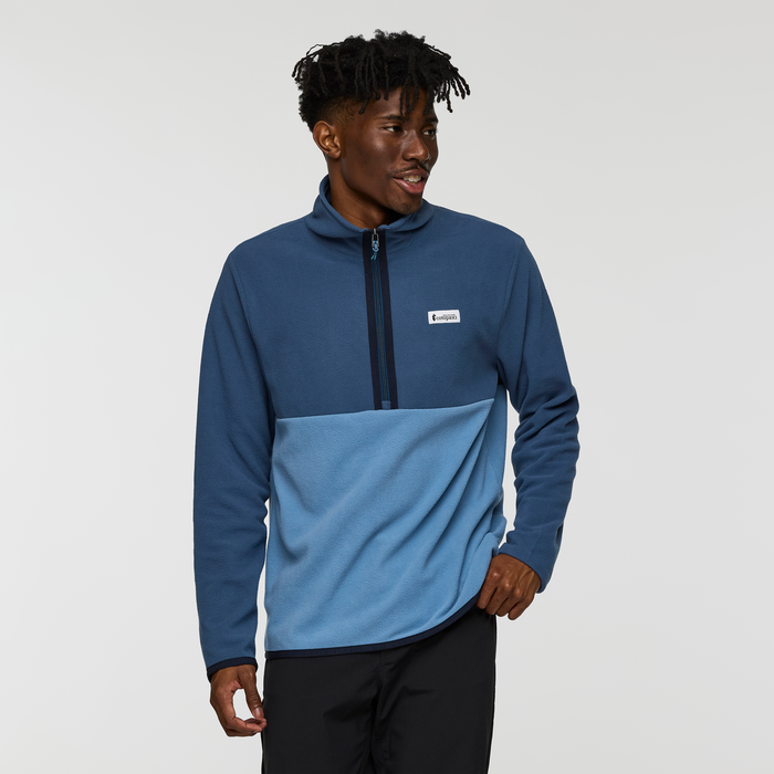 Male model wearing the Cotopaxi Amado Fleece Pullover in a two tone blue design with chest patch
