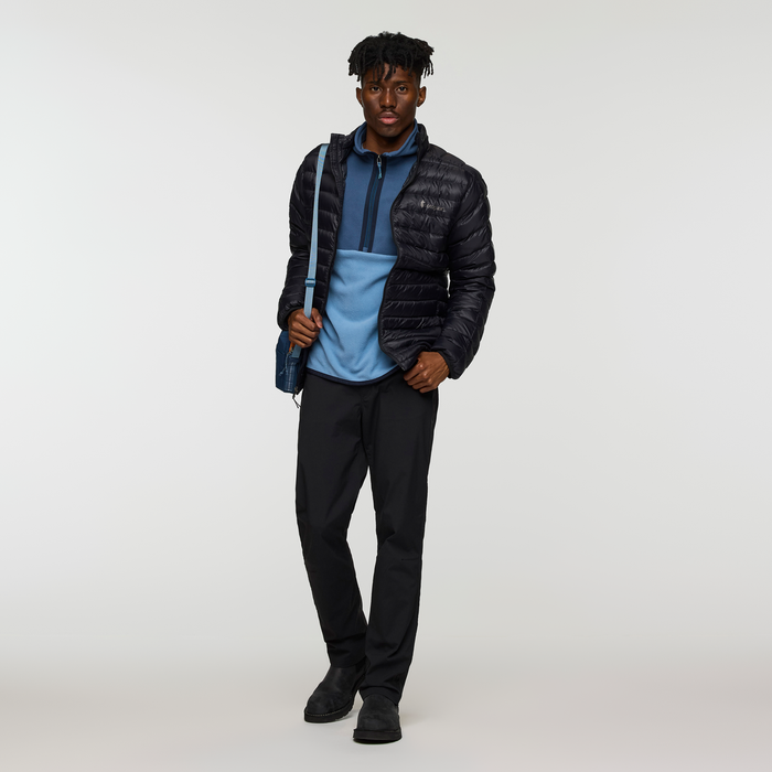 Male model in blue Amado Fleece under a black puffer jacket carrying a blue crossbody bag