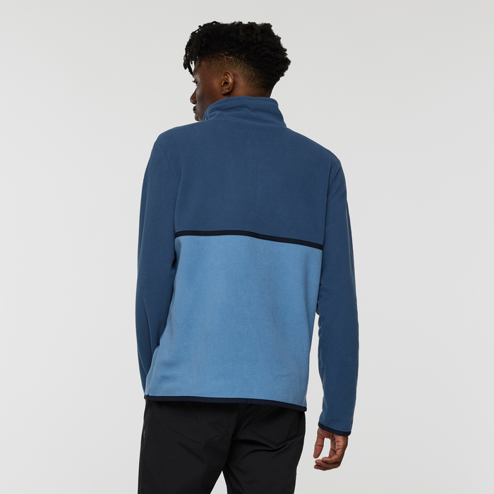 Back view of men's Cotopaxi Amado fleece pullover in dark and light blue with a color block across the back