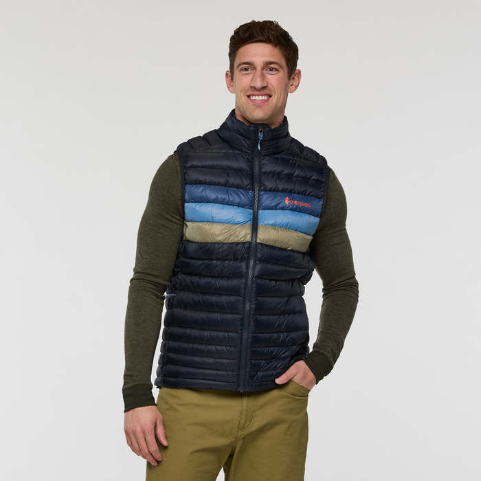 Man wearing navy Cotopaxi Fuego Down Vest with multicolor chest stripes and front zipper