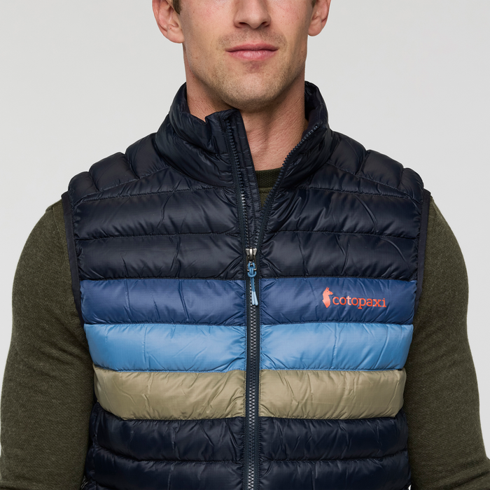 Front view of Cotopaxi Fuego Down Vest colorblocked in navy teal blue and tan with an orange logo on the chest.