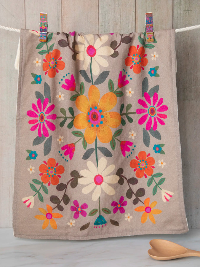 Taupe cotton dish towel with bright folk flower pattern hanging on a clothesline with clothespins