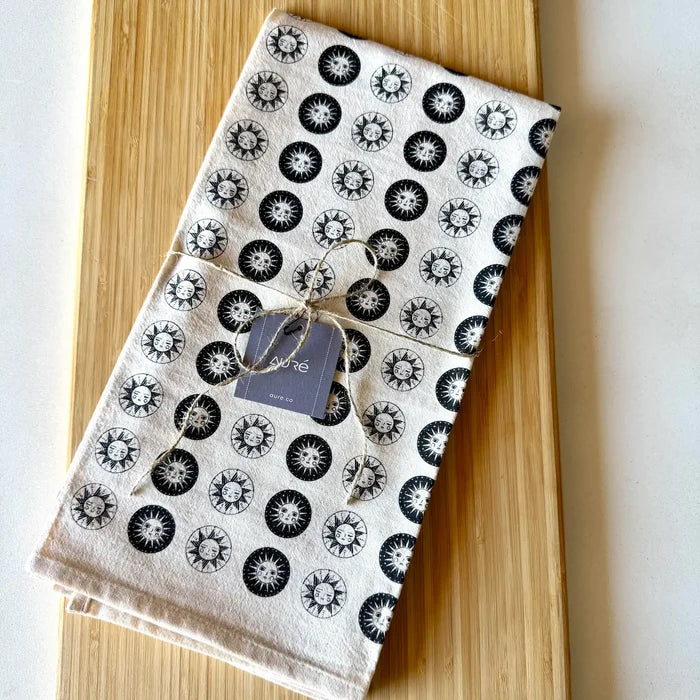 Folded cotton sun tea towel with black sun circle motifs on white, tied with twine and a tag