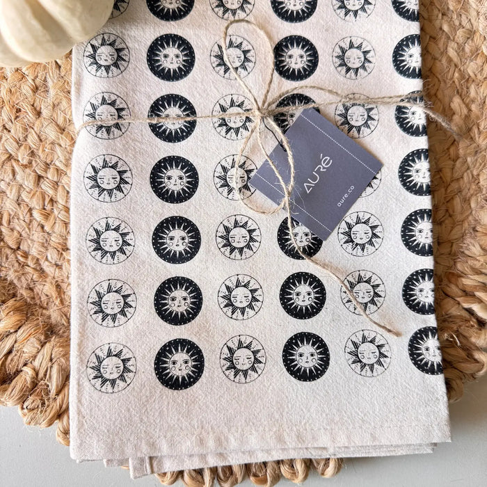 Close-up of cotton sun tea towel pattern featuring alternating black and white sun circles, tied with twine and lavender tag