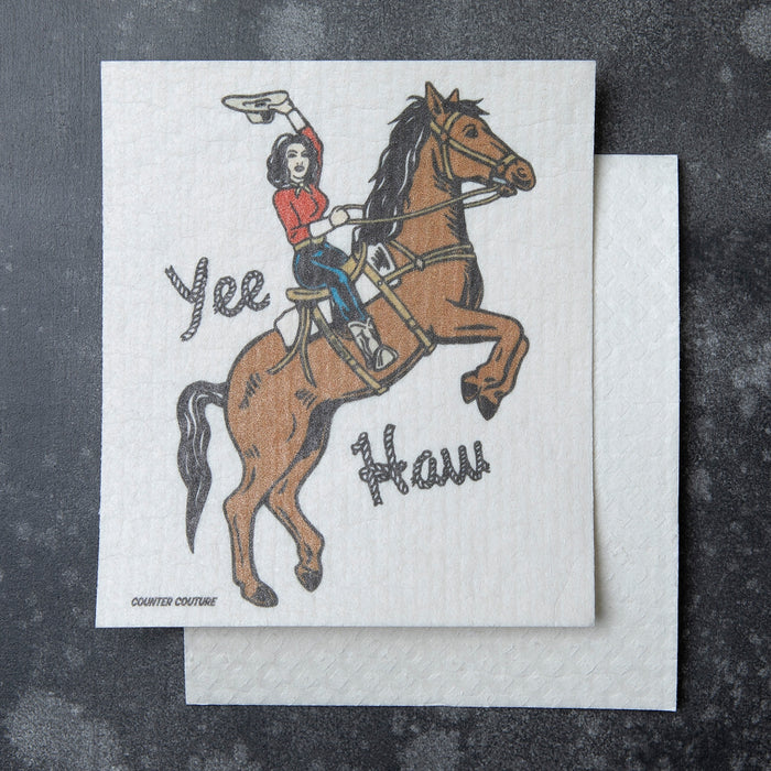 Cowgirl riding a bucking horse on a Swedish dishcloth with the words Yes and How