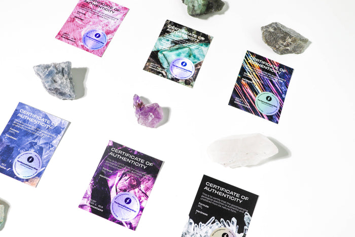 Crystal Blind Bag close up of crystals and three colorful Certificates of Authenticity in pink teal and rainbow designs