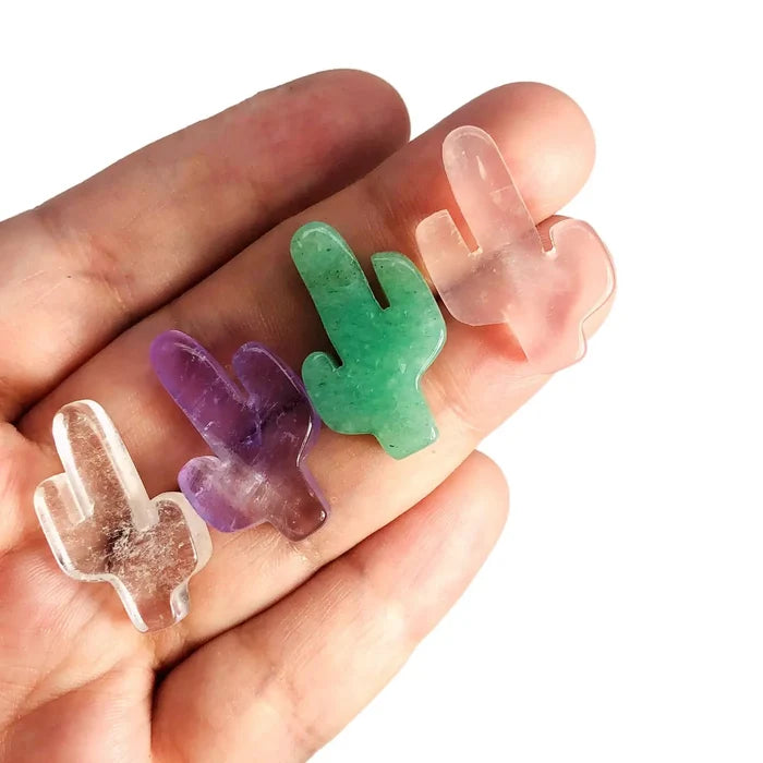 Assorted crystal cactus shaped gemstones in pink purple green and clear held in a hand