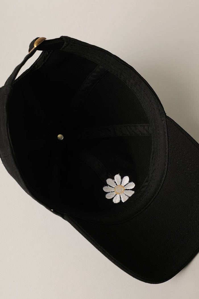 Inside view of black cap with white embroidered daisy near the crown and curved brim